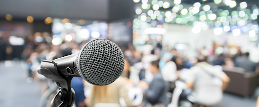 Close-up of a microphone with a blurred audience in the background.