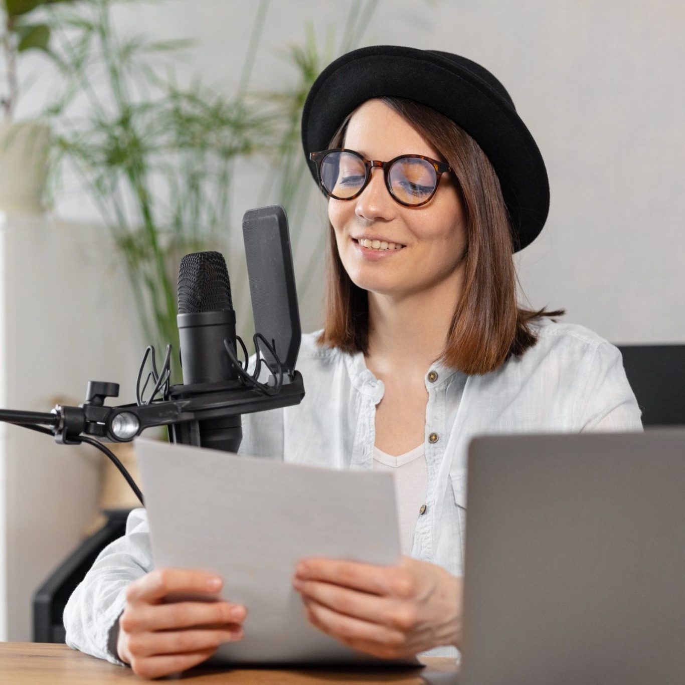 Woman in glasses reading from paper at a microphone with a laptop nearby.