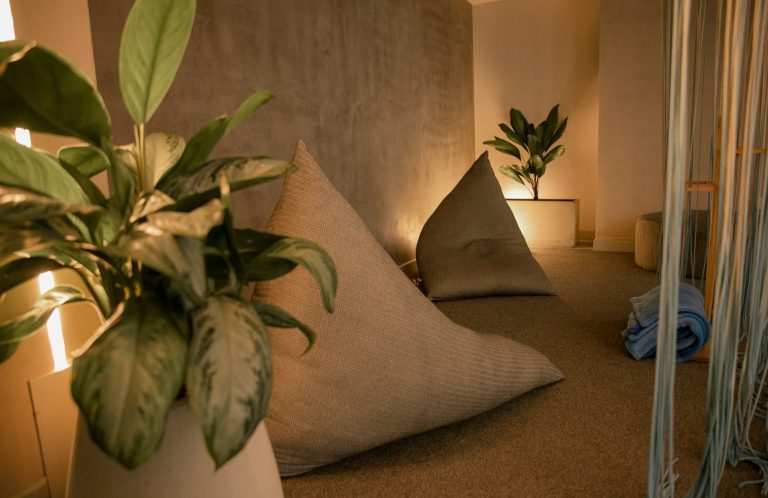 Cozy space with triangular cushions and potted plants, softly illuminated.