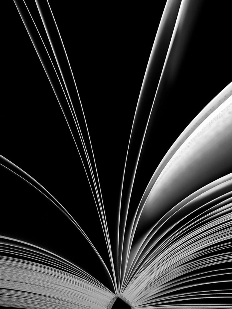 Open book with pages fanned out, set against a dark background.