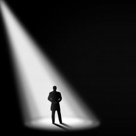 Silhouette of a man standing in a spotlight against a dark background.