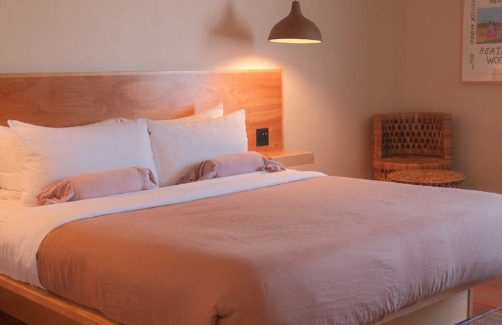 Cozy bedroom with a large bed, wooden furnishings, and natural light from large windows.