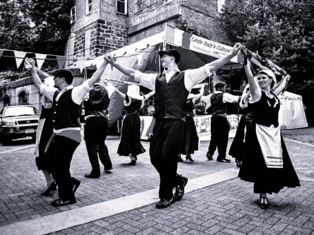 Traditional dancers in folk costumes perform in a lively outdoor festival.
