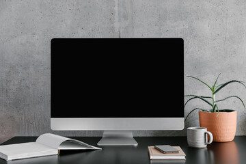 A sleek desktop computer on a desk, with a plant and a coffee mug nearby.