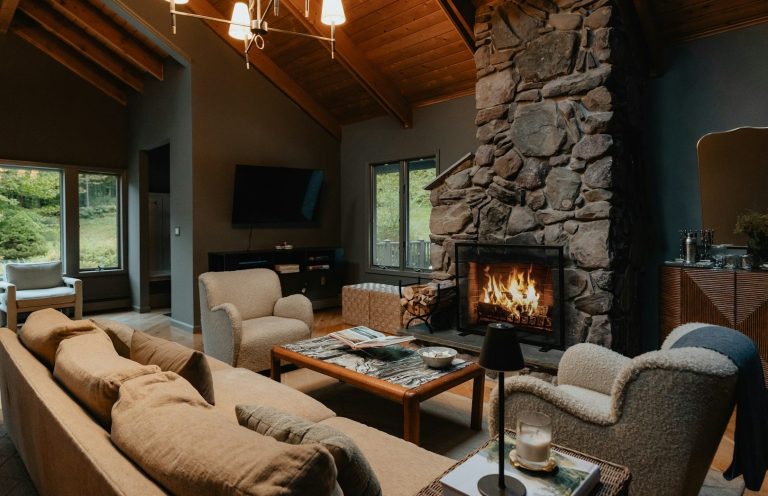 Cozy living room with a stone fireplace, comfortable seating, and large windows.