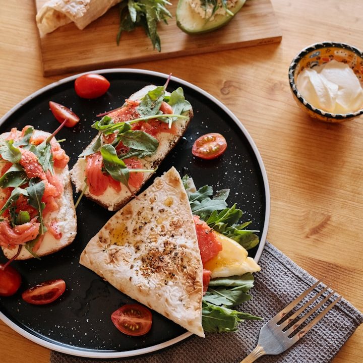 Three flatbreads topped with tomatoes, arugula, and cheese, served with yogurt and garnishes.
