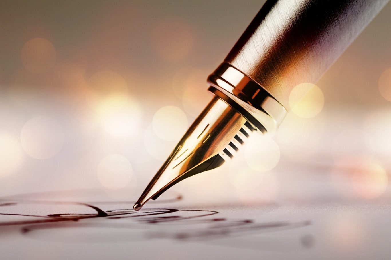 Close-up of a fountain pen poised above a handwritten line on paper.