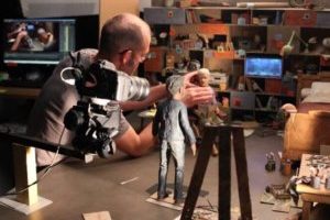 A person working on stop-motion animation with puppets and a camera.