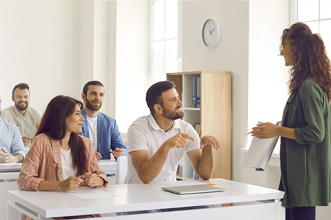 A person standing in front of a classroom engaging with attentive students.