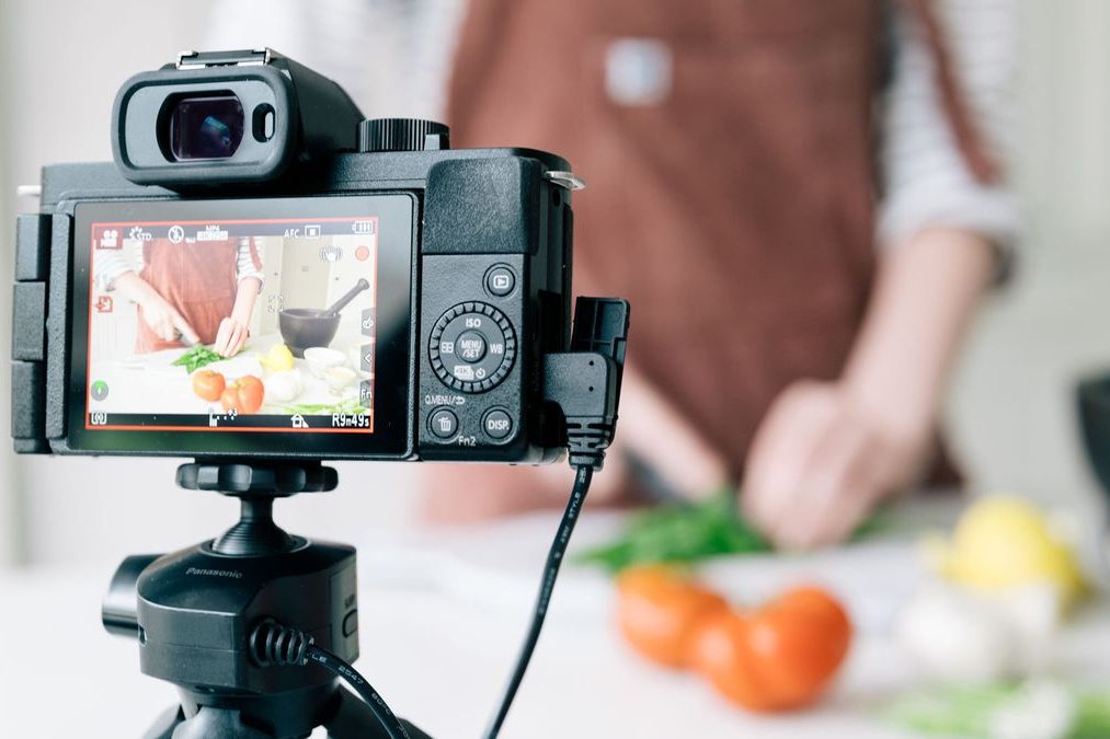 Camera focused on hands chopping vegetables with colorful ingredients on a kitchen counter.