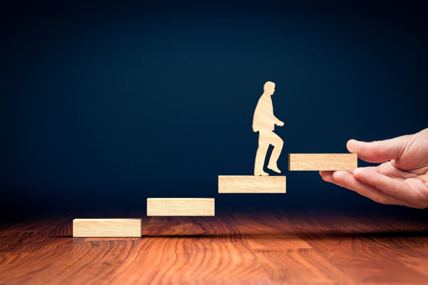 A hand holds steps with a figure ascending, symbolizing progress and growth.