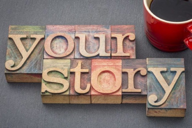 Wooden blocks spell "your story" next to a red coffee mug on a dark surface.