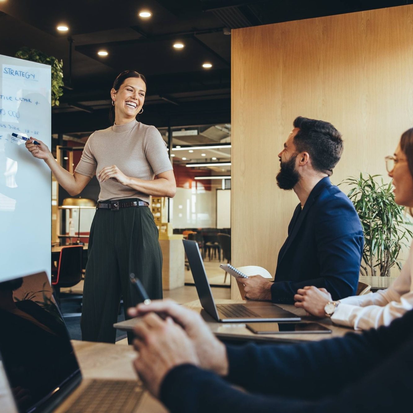 A woman presents ideas to a group in a modern meeting room.