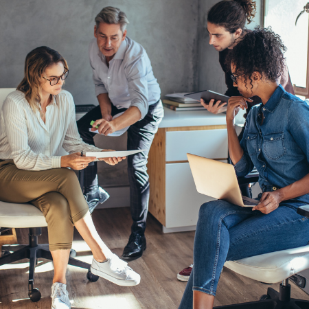 Four colleagues discussing a project in a modern office setting.
