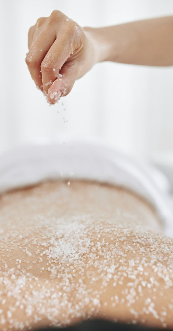 Salt Scrubs at Birch and Ink Retreat Hand sprinkling salt over a person's back during a spa treatment.