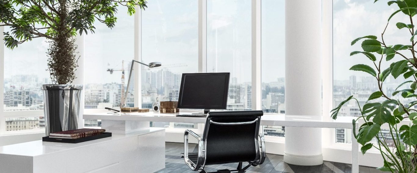 Modern office with large windows, greenery, and a sleek ergonomic chair.